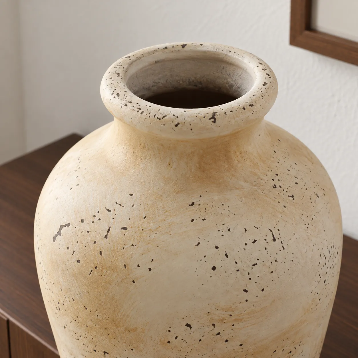 Close view of the flared rim and irregular dark flecks in the cream finish